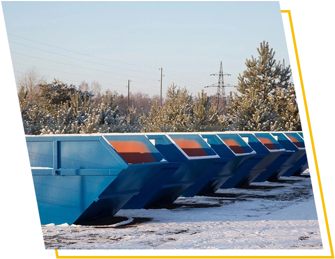 A row of blue and orange dumpster trucks in the snow.