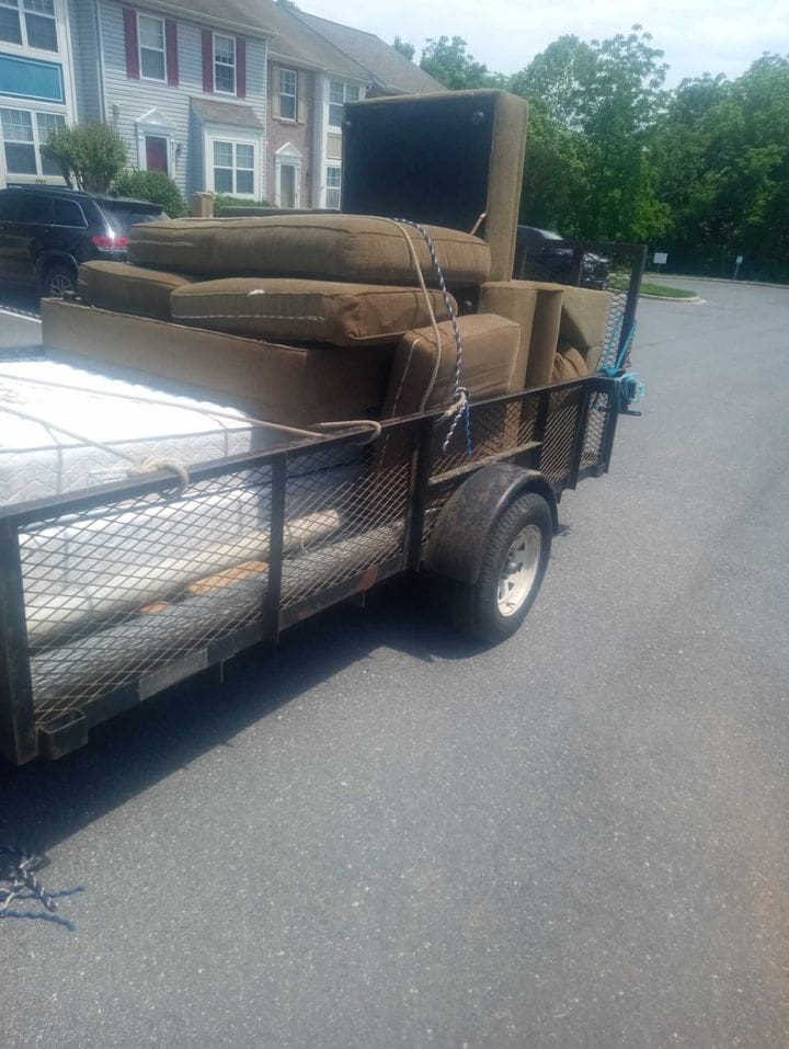 Open metal trailer piled with sofa pieces